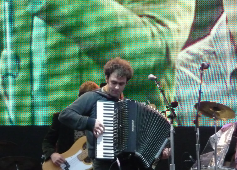 a man plays a musical instrument with other people watching