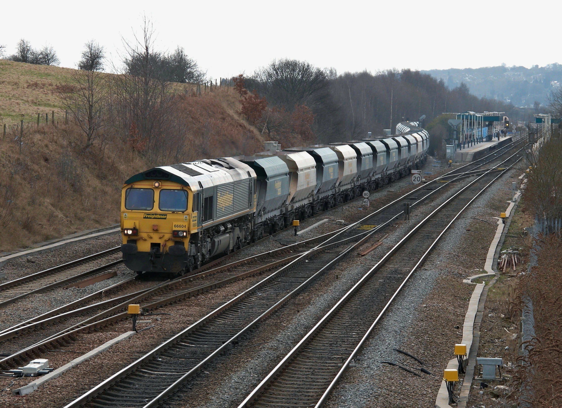 a freight train traveling down the track through a wooded area