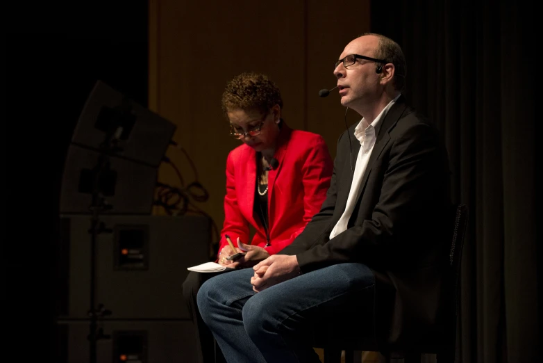 two people sit in front of a microphone