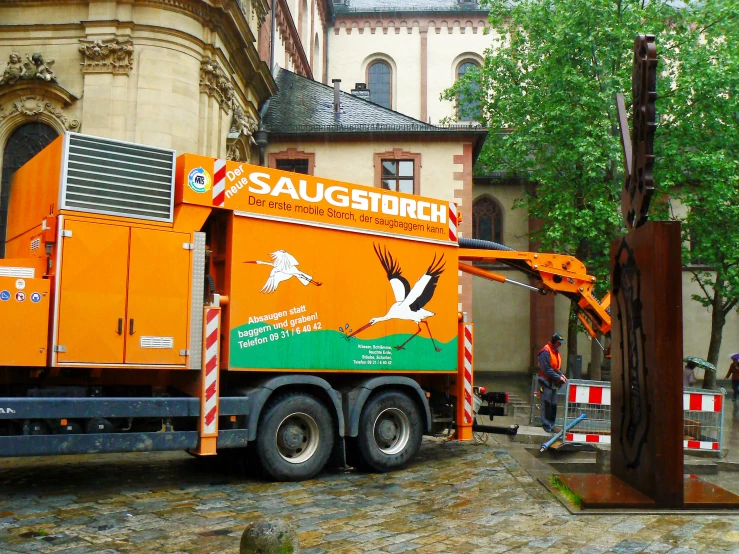 an orange truck is shown driving by a building