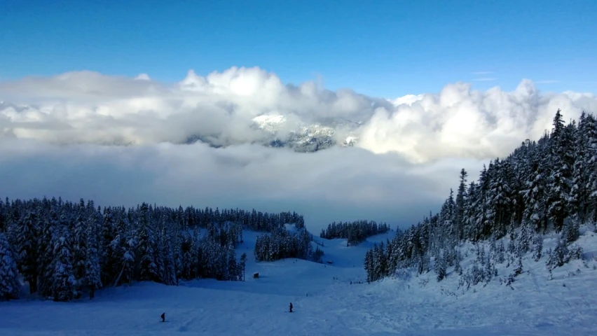 the clouds are above the trees and a hill