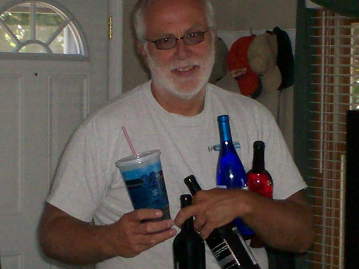 man holding two drinks and some liquor bottles