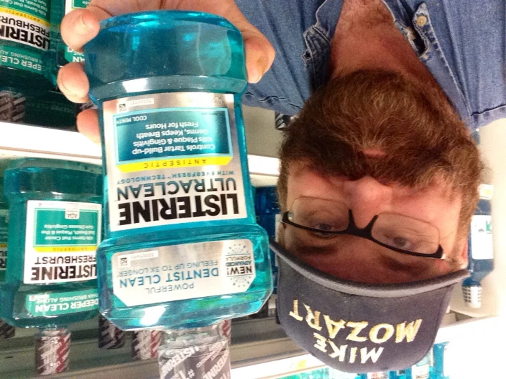 a man in glasses holding up a bottle of listerine