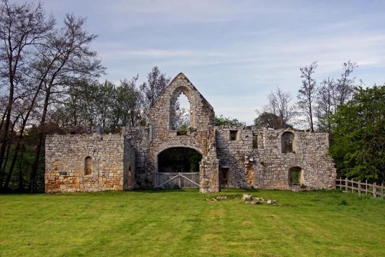 an old stone building with two gates on grass