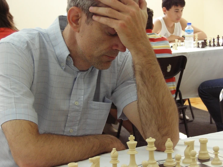 man sitting down playing chess in a white room