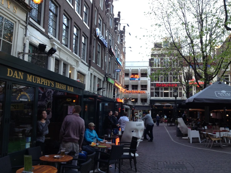 many people eating outside an outside restaurant in a city