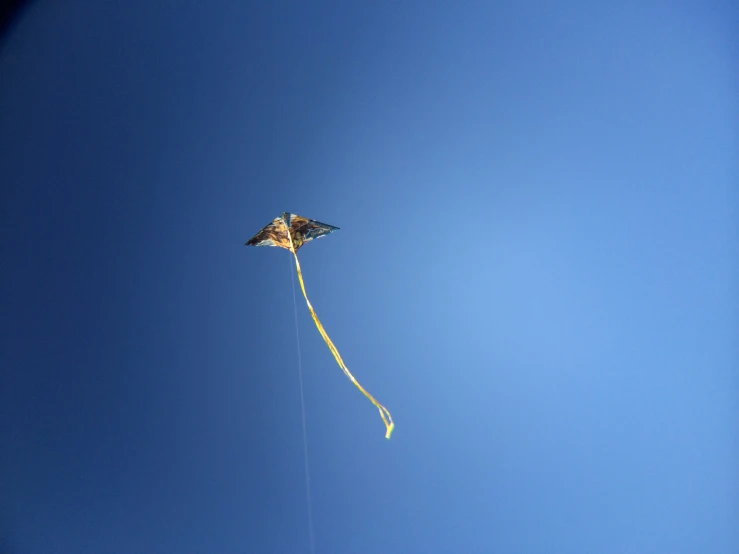 a kite flying through a blue sky in a clear day