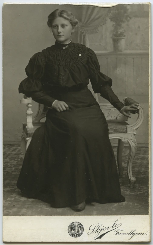 old - fashioned po of a lady in long dress seated in a chair