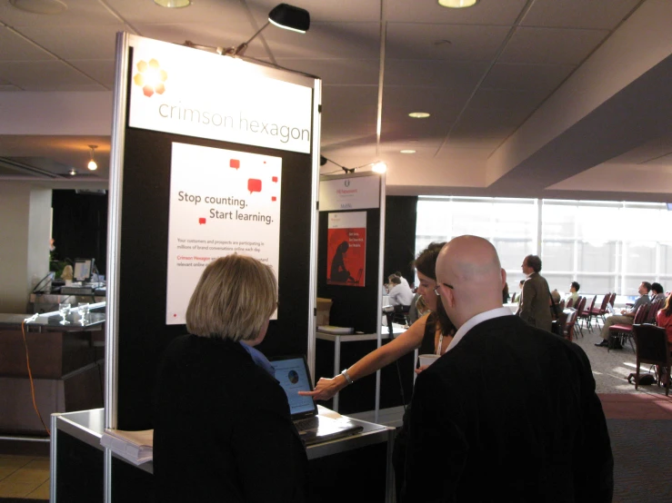 people in suits and ties standing near an exhibition poster