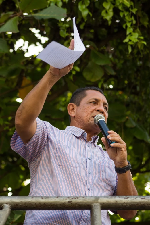 man holding microphone with papers above him while talking