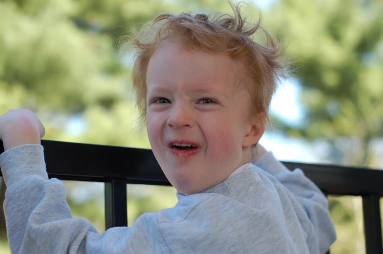 a little boy standing on a rail with his hair in the air