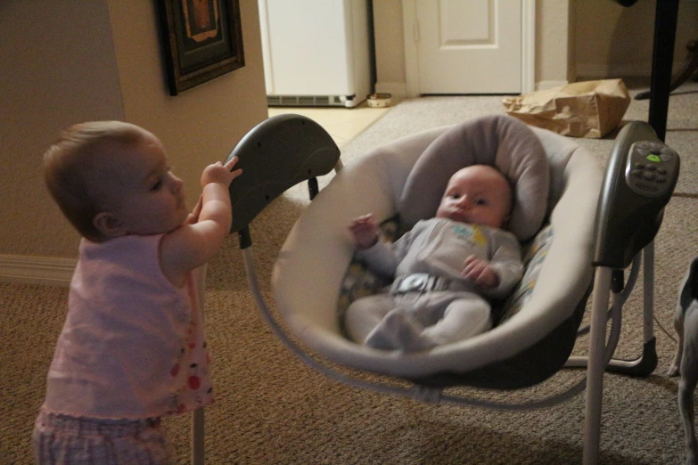 two toddlers interacting in the room and facing the ground