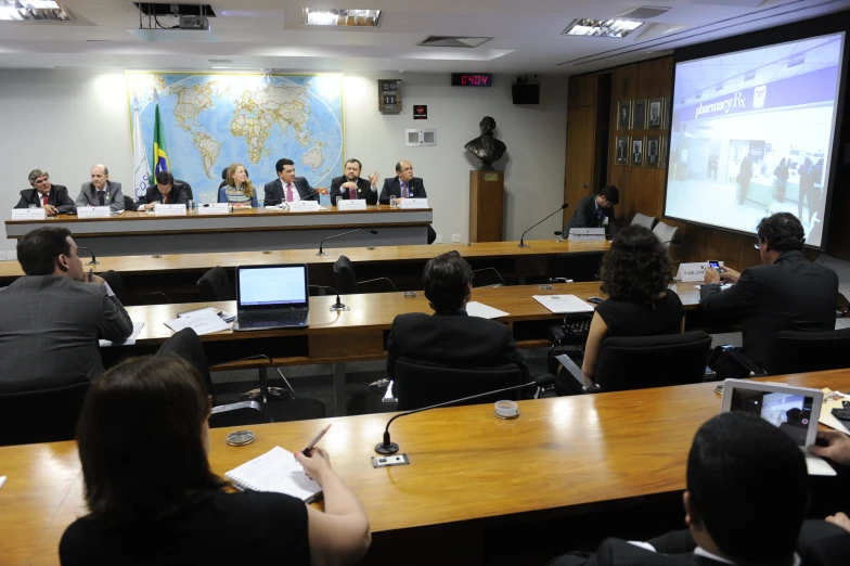 people in black are sitting at a conference room table and talking to one another