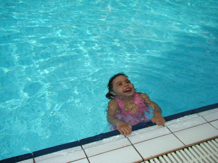 a little girl in the pool smiling for the camera