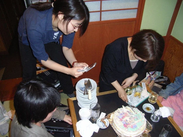 three asian girls, one in blue shirt, sitting at table