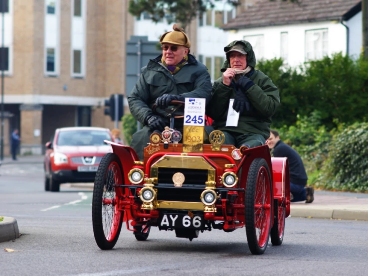 a group of men riding on the back of a red and yellow car