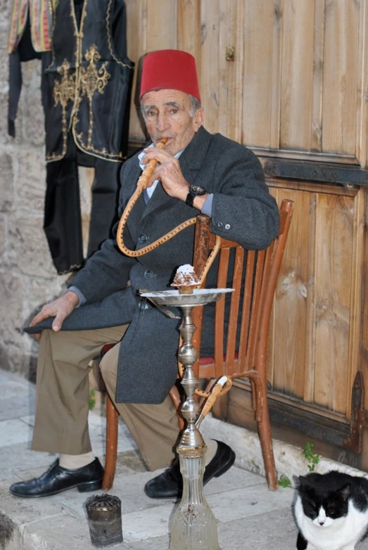 an old man sitting next to his cat outside