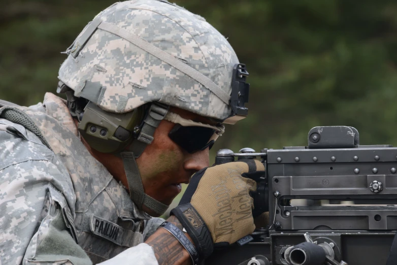 a soldier in camouflage, taking a close up of his rifle