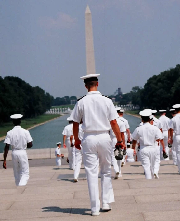 sailors walking on a paved area in front of the national monument