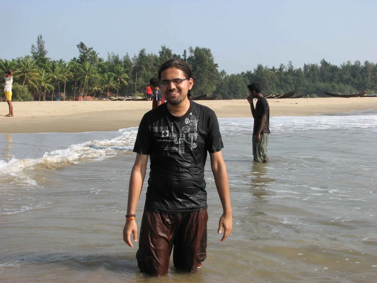 a young man smiles at the camera as he stands in shallow water