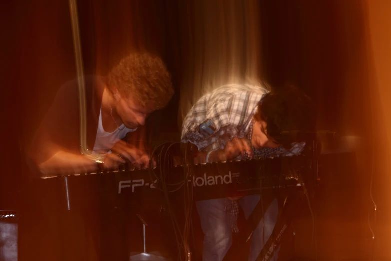 a man playing piano while another plays on the keyboard