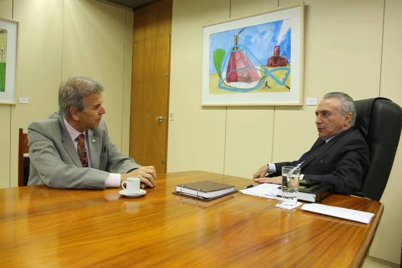 two men sitting at a desk having a discussion