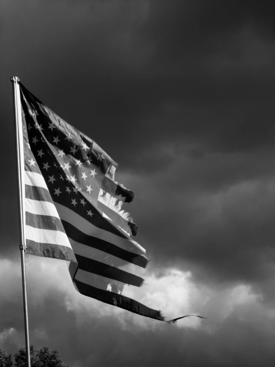 a large american flag waving under the cloudy sky