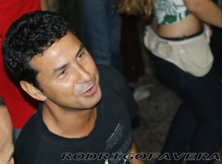 man standing in a crowd wearing a black shirt and looking to his right