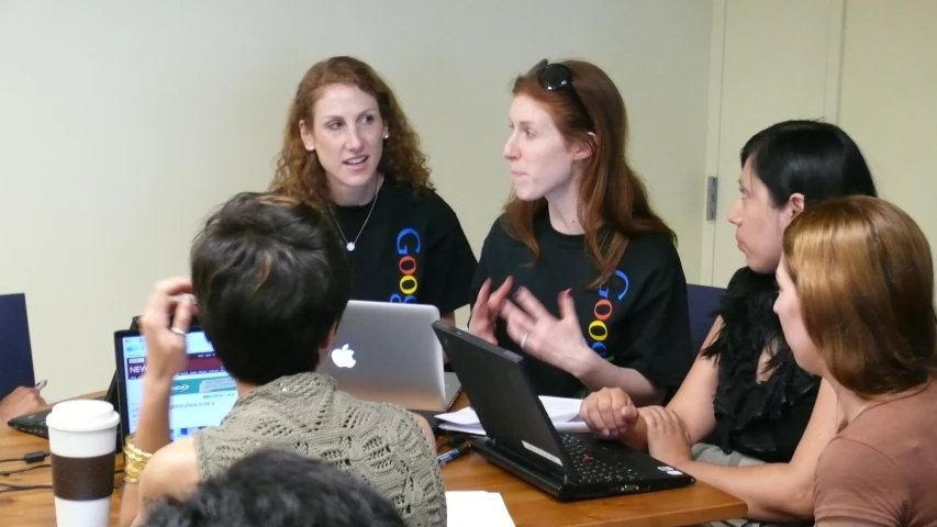 several women are at a conference table discussing soing