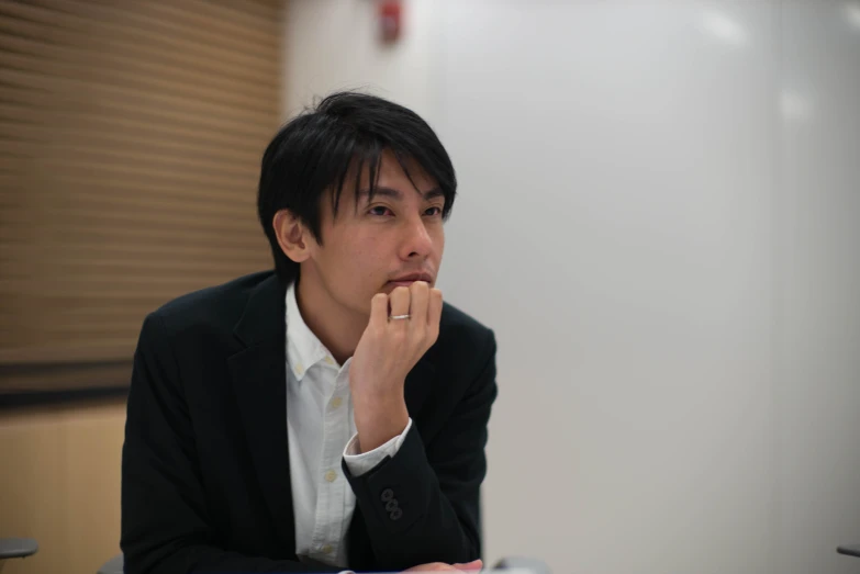 a man with his finger on the chin sitting at a table