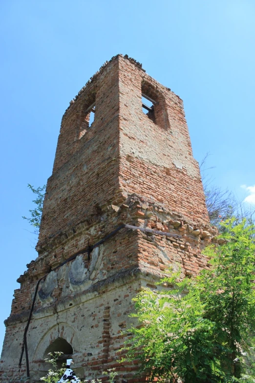 an old tower is near some trees and some blue skies