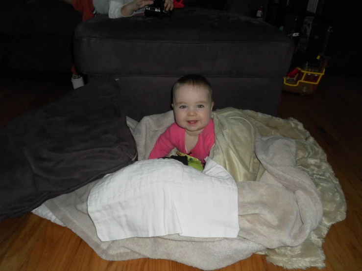 a toddler sits in a chair on blankets