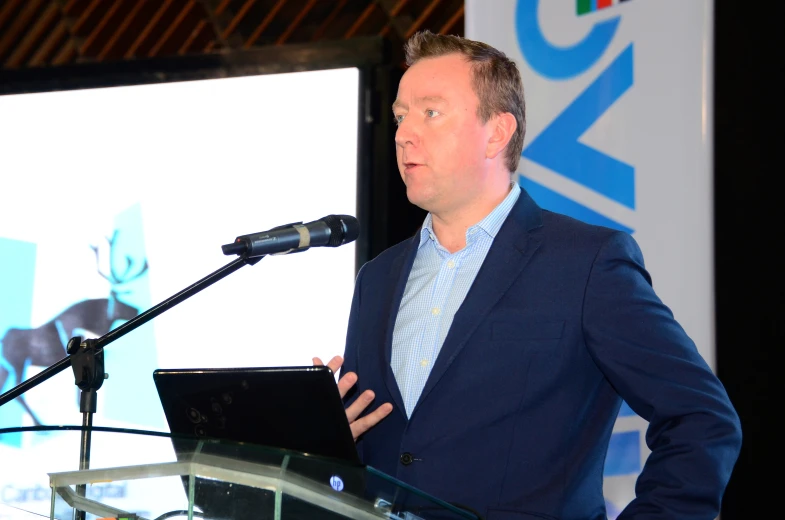 a man in a suit speaking in front of a microphone