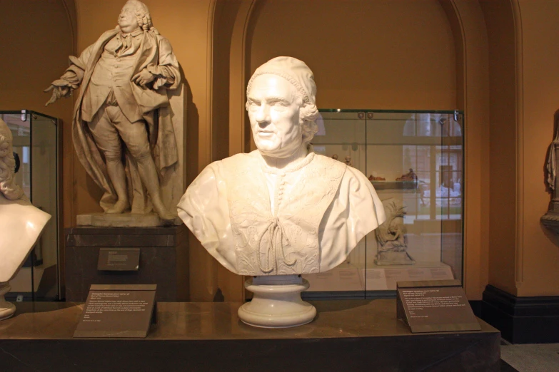 two marble busturines of men sitting side by side on a shelf