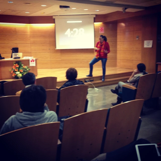 woman presenting on a podium with speakers in front of her