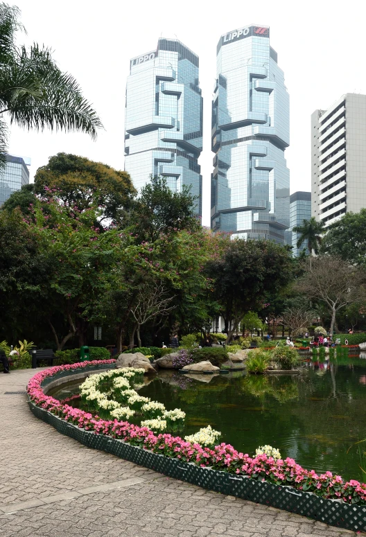 a park with water and flower beds next to two buildings