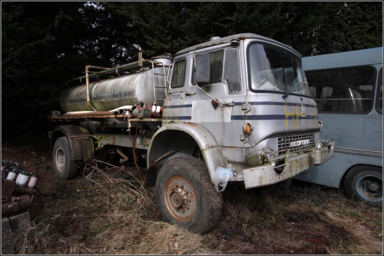 an old, white truck with an old rusty engine sits near a tree