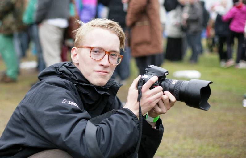 a man holds up a camera while in front of many people