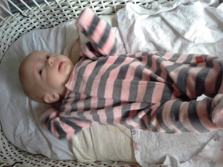 a baby in a striped pajamas laying down on top of a blanket