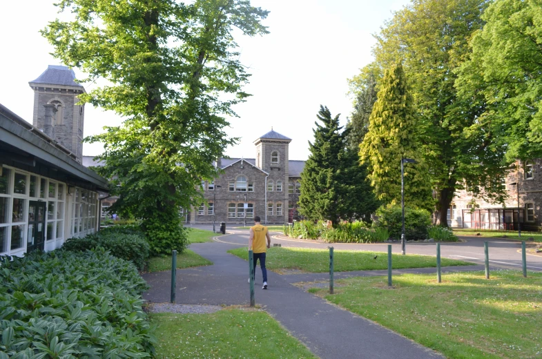 man walks down a pathway past two buildings