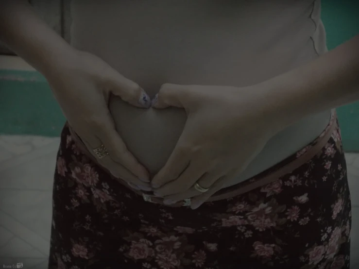 woman holding her belly in heart shape with both hands