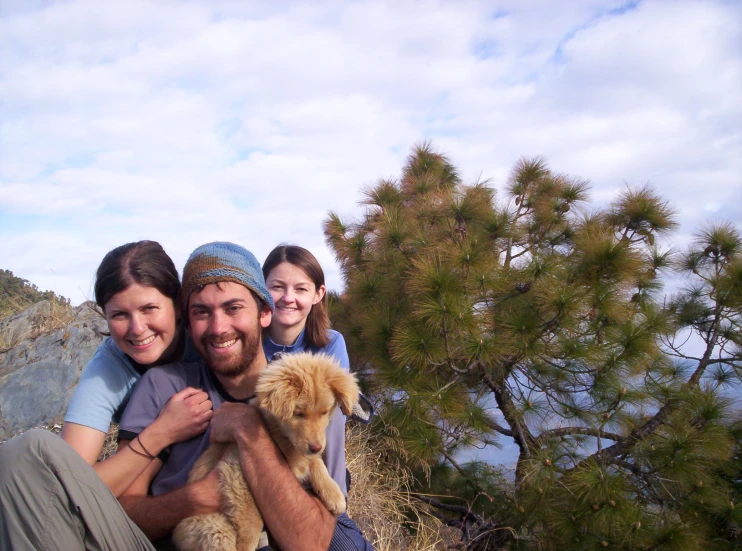 three people are holding a dog outside