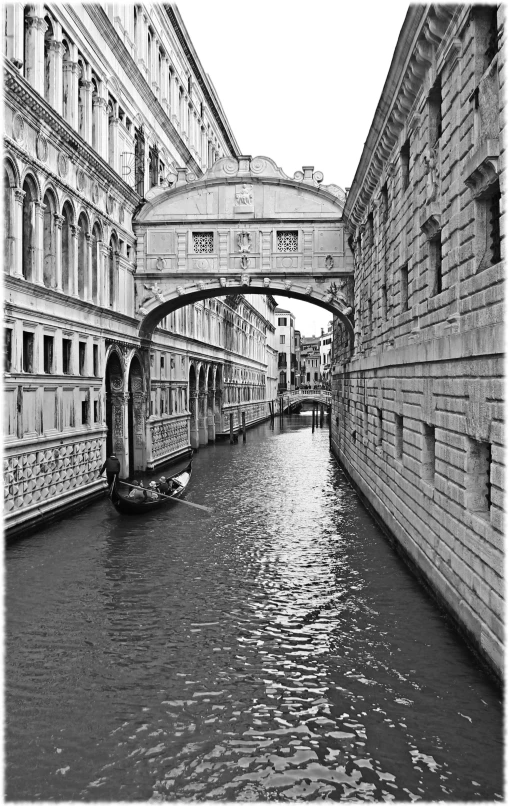 a black and white po of a boat coming under an arch in a canal