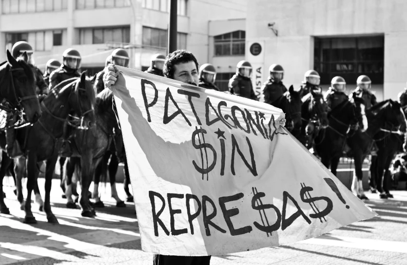 two women holding a sign in front of some horses