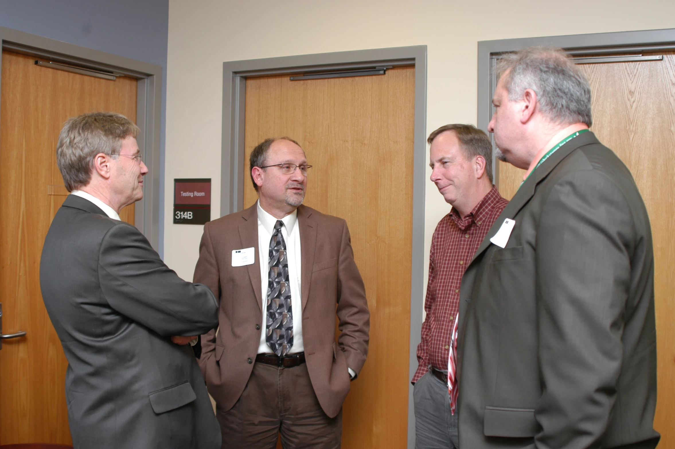 three men standing together talking and laughing near door