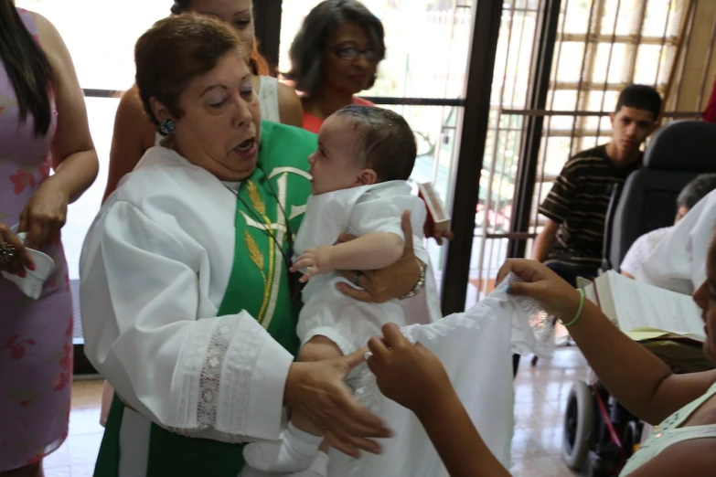 the priest is holding the baby during a ceremony