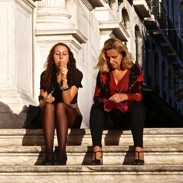 two girls sit on the steps in the city