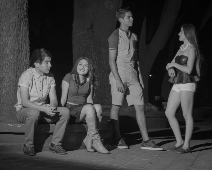 several people are gathered in front of a tree on the sidewalk