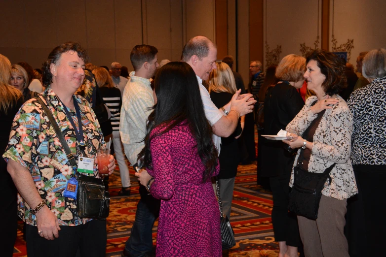 a group of people standing in a room talking and laughing