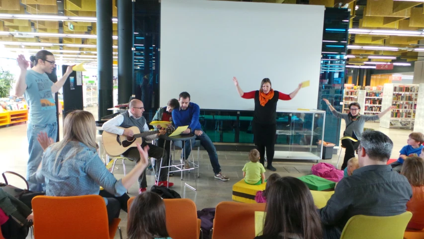 people playing guitar and singing and others sitting in chairs